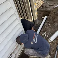 Plumber working on outdoor drainage pipework, Malvern