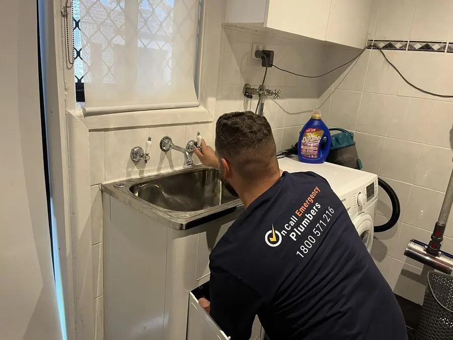 Plumber inspecting laundry sink plumbing, Malvern